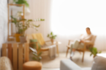 Woman reading book in modern living room, blurred view