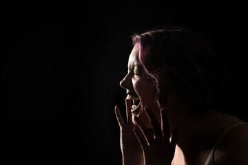 Silhouette of screaming young woman on black background