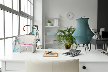 Organizer, stationery supplies and calculator on table in light office