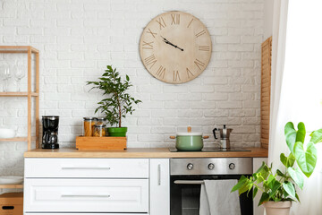 Big clock hanging on white brick wall in kitchen