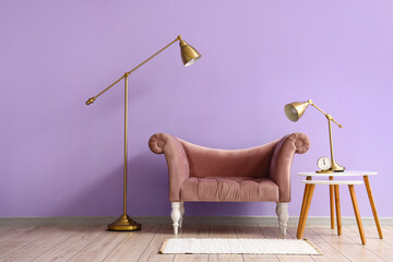 Stylish armchair, table and lamps near color wall in room interior