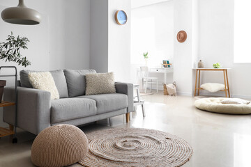Comfortable sofa near white wall in stylish room