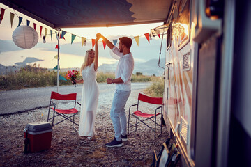Beautiful couple in nature in boho style, dancing in front of camper rv. Wedding, togetherness, love, travel, nature concept.