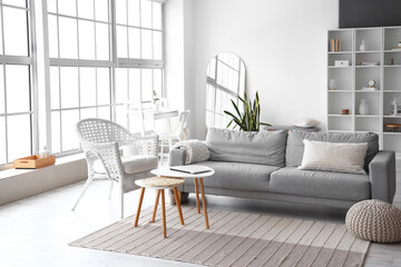 Interior of stylish living room with comfortable sofa, armchair and table with laptop