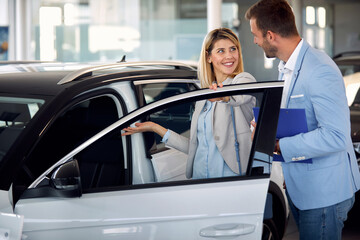 Fototapeta na wymiar Woman with salesman standing near new car
