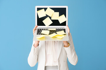 Young woman with sticky note papers on laptop against blue background