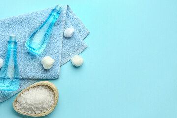 Bottles of cosmetic products, cotton balls, clean towel and sea salt on color background