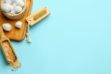 Composition with cotton balls, massage brush and sea salt on color background