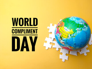 Earth globe and white puzzle with text WORLD COMPLIMENT DAY on a yellow background.
