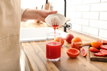 Woman making fresh orange juice in kitchen