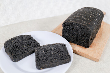 Black bread loaf slice on a white background.	
