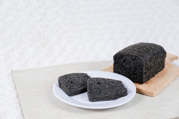 Black bread loaf slice on a white background.	
