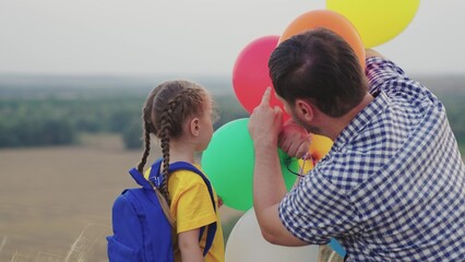 little child girl with her father plays colorful balloons inflated with helium. happy family park. childhood dream fly. kid daughter with dad holiday. family vacation travel nature. children vacation.