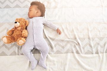 Little boy, big dreamer. High angle shot of a little baby boy sleeping on a bed with a teddy bear.