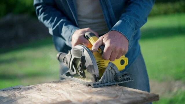 Close-up of craftsman working with circular saw at construction site
