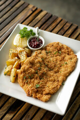 german veal schnitzel cutlet with potato and red berry sauce