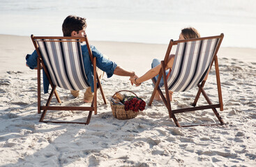 Here for the ocean waves and lazy days. Rearview shot of a middle aged couple sitting in their...