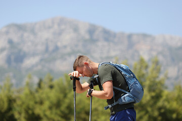 Tired man with Scandinavian walking sticks on mountain