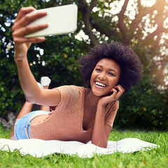 Nature makes for the best background in selfies. Shot of a young woman taking a selfie white at the park.