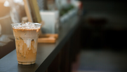 Ice coffee on a plastic cup with cream being poured into it showing the texture