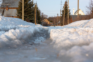 Snow and water on the road in the spring in the village on the street.