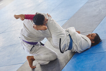 Whos in control here. Full length shot of two young martial artists practicing jiu jitsu in the gym.