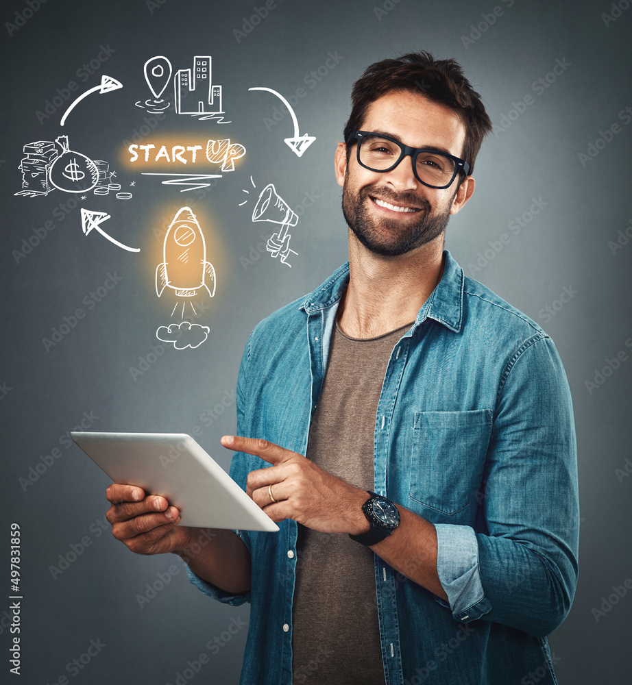Poster Im working on something big. Studio portrait of a handsome young man browsing on a digital tablet while standing next to illustrations against a grey background.