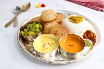Indian vegetarian lunch or dinner Thali includes Aloo ki sabji, dal rice, Puri bhaji, Shrikhand or...