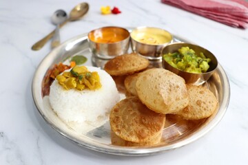 Indian vegetarian lunch or dinner Thali includes Aloo ki sabji, dal rice, Puri bhaji, Shrikhand or...