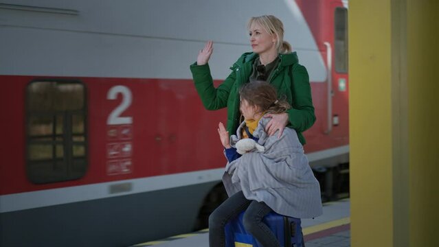 Ukrainian woman with daughter saying good bye and waving to his family in train leaving Ukraine due to Russian invasion in Ukraine.