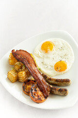 australian breakfast with fried eggs, sausage, bacon and potato
