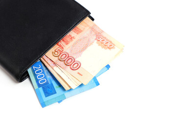 Russian rubles in denominations of two and five thousand rubles in a purse on a white background.