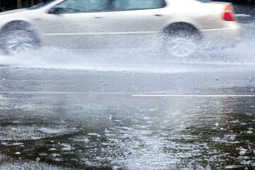 car driving on city road on fast speed creating water splashes