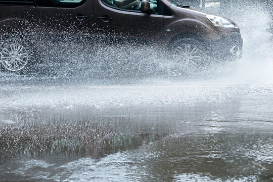 car rides through puddles on a wet street with splashing water