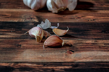 Fresh garlic bulbs and a garlic press on an old wooden board and a burlap backing.