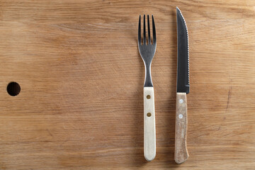 cutlery lie on the oak table top, vintage steak  knife and fork on the right side , top view, copy space