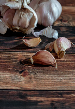 Fresh garlic bulbs and a garlic press on an old wooden board and a burlap backing.