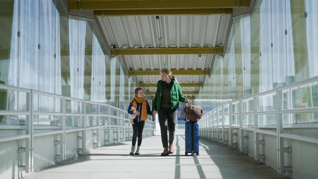 Ukrainian immigrant mother with child with luggage walking at train station, Ukrainian war concept.