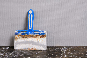 Spatula for finishing and plastering walls on a gray wall background.
