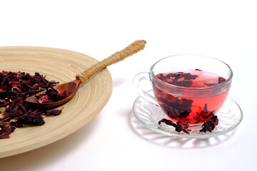 Dried leaves Sudanese rose wooden dish and cup of brewed tea on white, herbal tea karkade.