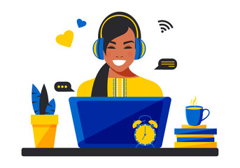 A Ukrainian woman in an embroidered shirt and headphones works remotely with a laptop in a support center. Home office during quarantine due to coronavirus. Online education and training. 