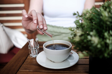 Close up of woman hand putting sugar in a coffee.