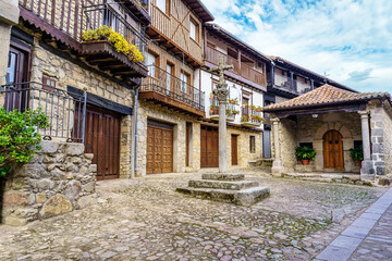 Village square with old traditional houses and stone cross, Mogarraz Salamanca. - obrazy, fototapety, plakaty