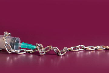 Drug addiction. An empty medical syringe is wrapped with a chain 