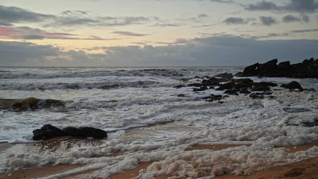 Sunrise seascape with sea foam and rain clouds
