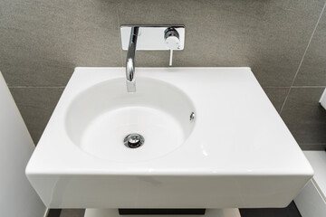 Metal faucet and white ceramic sink in modern bathroom.
