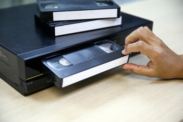 Close-up hand put or insert video cassette tape VHS old retro style on video record playback concept of vintage electric and electronic appliances multimedia player device old fashioned. © Eakrin