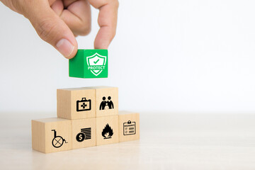 Close-up hand chooses cube wooden toy blocks stacked with prevent protect icon for safety safeguard family insurance and shield proof concepts.