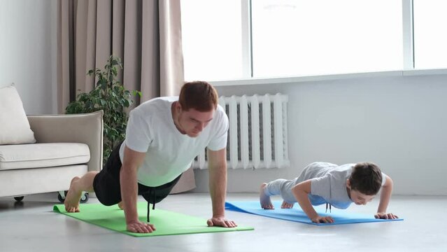 father and son are doing push-ups and having fun at home. diverse family. Sporty toned dad and boy child follow healthy lifestyle exercise taring together. Sport concept.