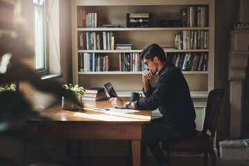 Giving this some careful thought. Shot of a young businessman looking thoughtful while working on a...